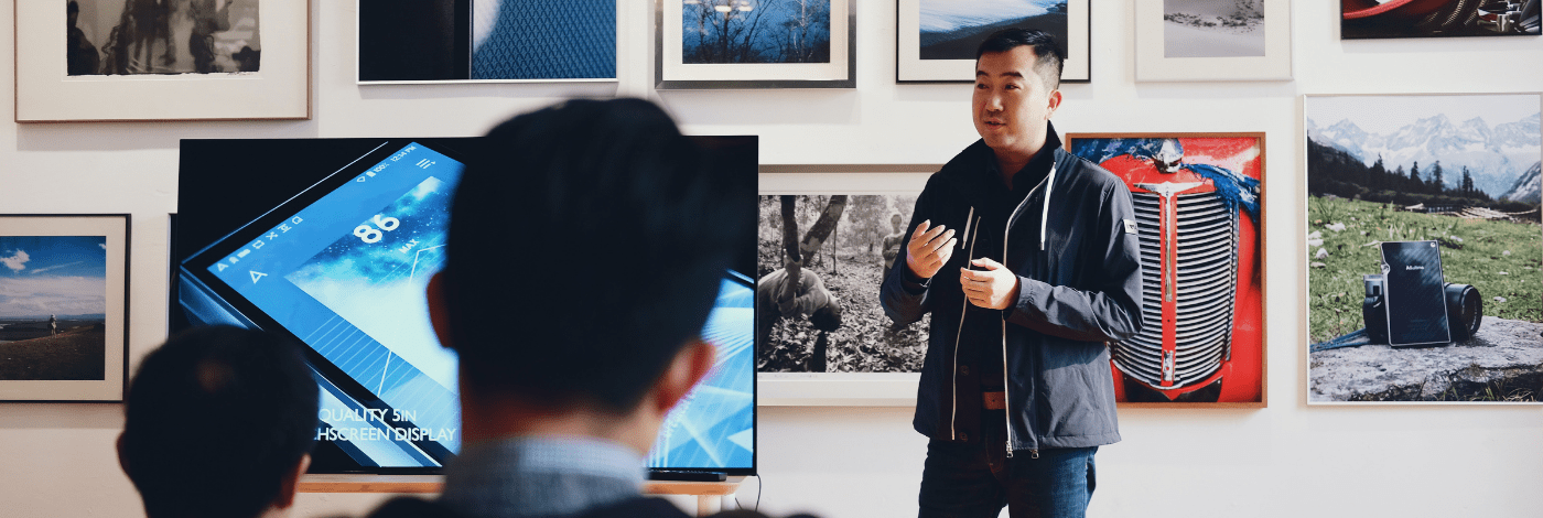 A man standing in front of a large screen, possibly presenting or engaging with digital content.